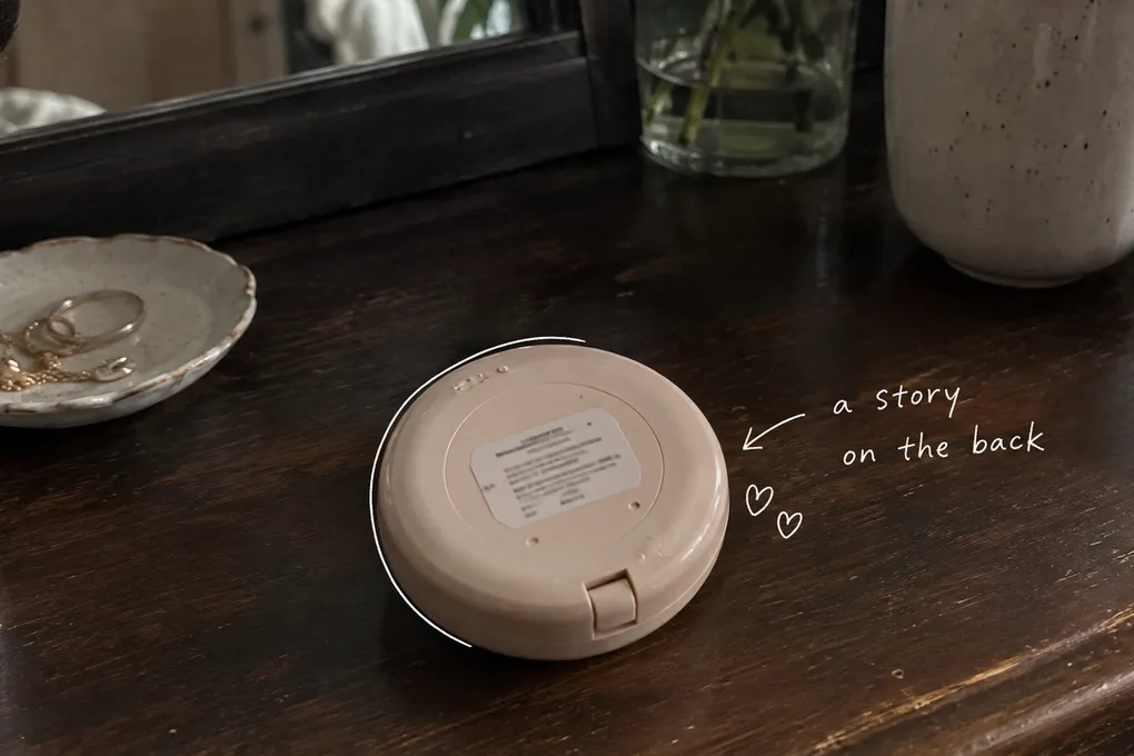 AI-generated scene of an unbranded makeup compact turned upside down on a wooden vanity, with a small label and white handwritten notes.