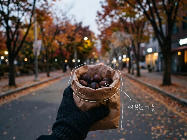 낙엽 쌓인 가로수길에서 장갑 낀 손이 김이 오르는 군밤 종이봉투를 든 AI 생성 이미지. 봉투에 흰 선이 얹혀 있고 '따끈한 가을' 손글씨가 있다.