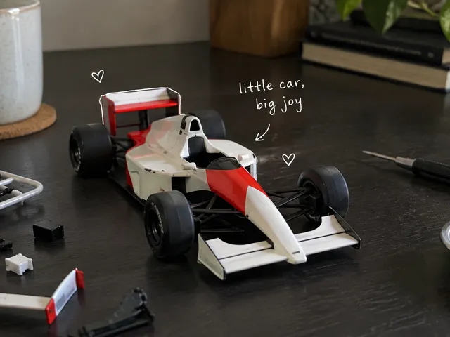 AI-generated model racing car and small assembly tools on a desk, with a white handwritten note.