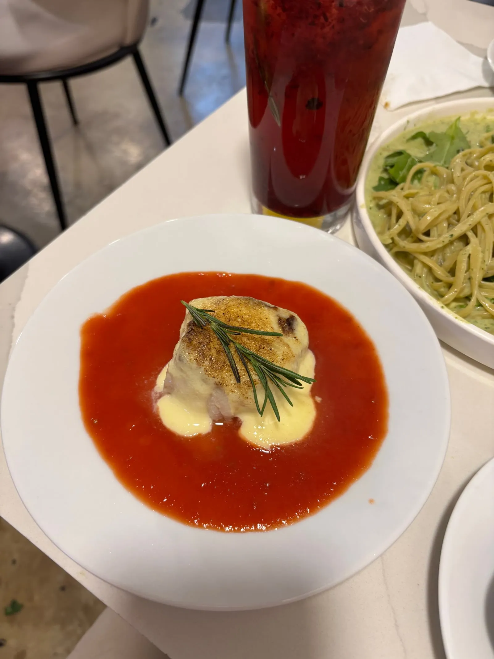 A plate of golden-baked cod with rosemary on red tomato sauce