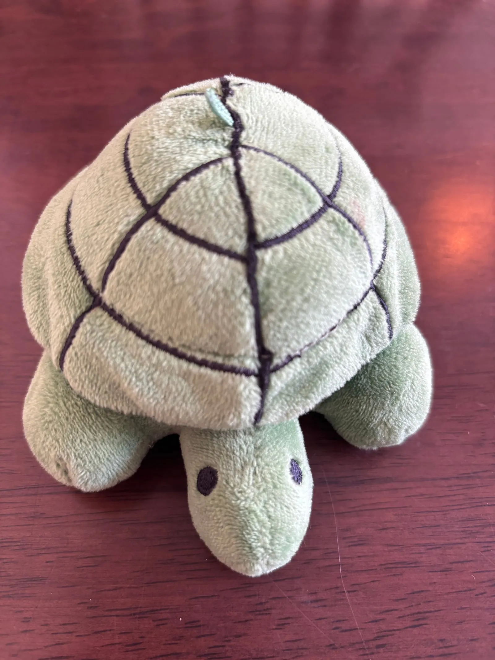 A small green plush turtle with a shell pattern used as a vibrating buzzer