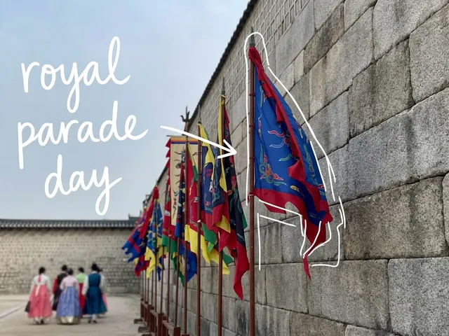 AI-generated view of colorful traditional banners along an old palace stone wall, with people in hanbok walking far ahead, thin white lines and the handwritten note 'royal parade day'.