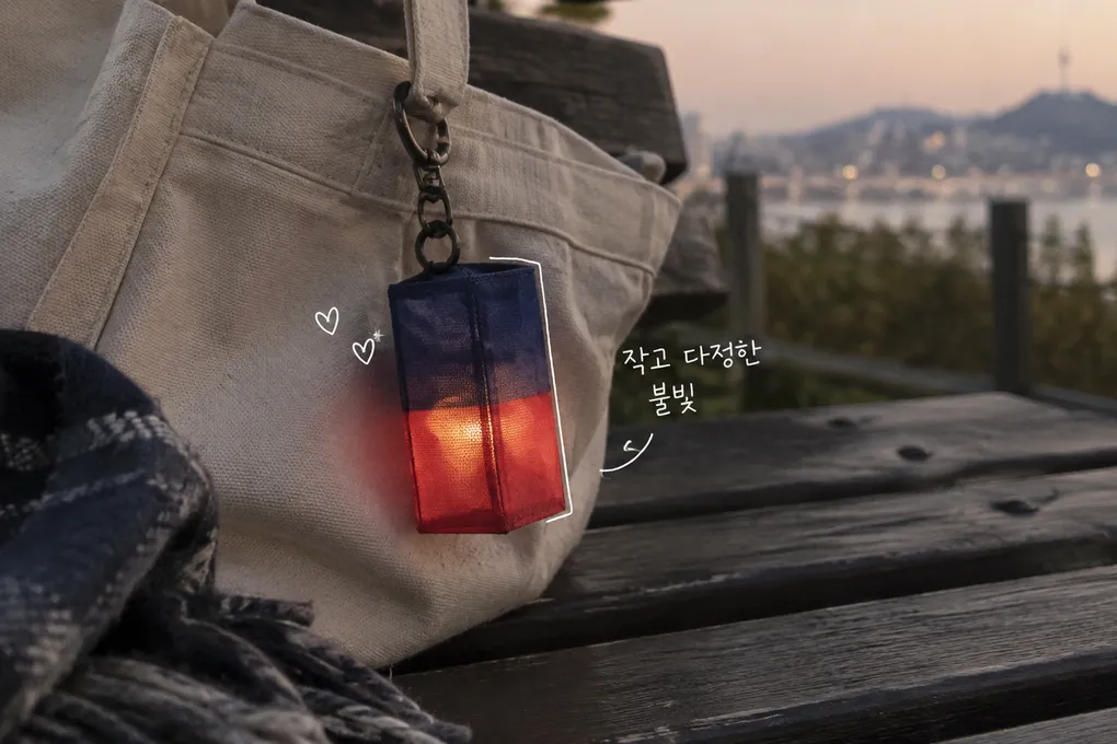 천 가방에 달린 청색·홍색 등불 키링과 흰 손글씨를 그린 AI 이미지로, 실제 판매 상품을 재현한 사진은 아닙니다.