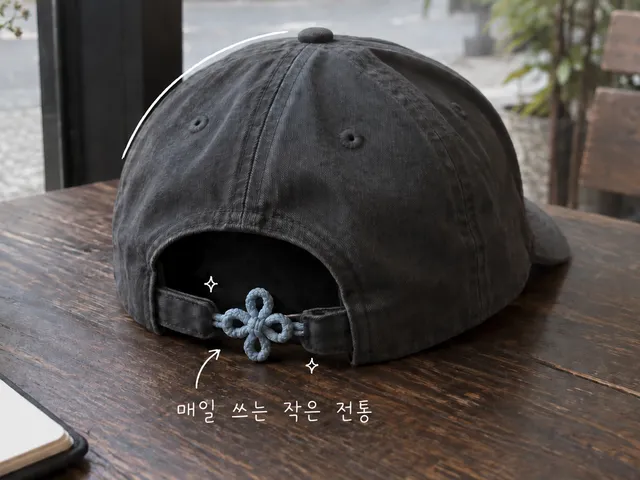 뒤쪽에 장식 끈 매듭이 달린 어두운 야구 모자를 그린 AI 생성 일러스트와 작은 흰 손글씨.