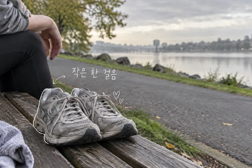 강변 벤치 위에 놓인 낡은 러닝화와 익명의 앉은 사람, 작은 한 걸음이라는 손글씨를 담은 AI 생성 이미지.